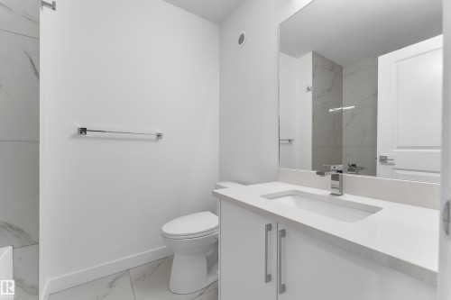 Modern bathroom featuring a white vanity with a rectangular sink, a chrome faucet, and a large mirror - 114 Mitchell Bend, Leduc, AB - Indoor Photo Showing Bathroom