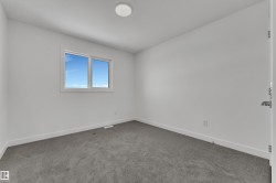 This room features a window providing natural light, white walls, and grey carpeting - 