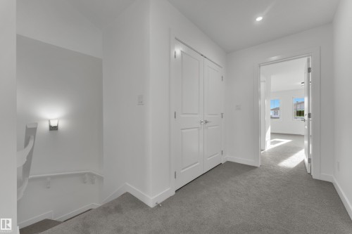 The property features a hallway with light gray carpet, white walls, and white trim - 114 Mitchell Bend, Leduc, AB - Indoor Photo Showing Other Room