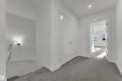 The property features a hallway with light gray carpet, white walls, and white trim - 