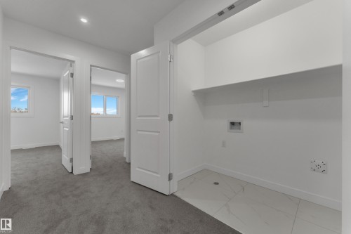 This property features a dedicated laundry area with tiled flooring and a built-in shelf - 114 Mitchell Bend, Leduc, AB - Indoor Photo Showing Other Room