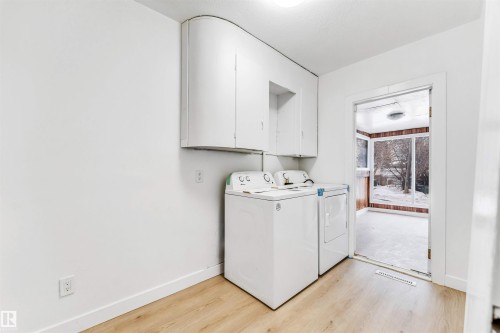 Dedicated laundry area featuring white cabinetry, light-colored flooring, and a view of the exterior through a glass enclosure - 12423 91 Street, Edmonton, AB - Indoor Photo Showing Laundry Room