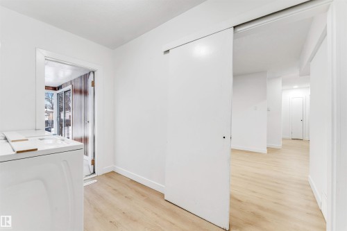 This bright space features light-toned flooring, white walls, and a sliding barn door - 12423 91 Street, Edmonton, AB - Indoor Photo Showing Laundry Room