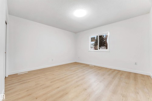 Bright interior room featuring light wood-look flooring, white walls, and a window providing views of outdoor trees - 12423 91 Street, Edmonton, AB - Indoor Photo Showing Other Room