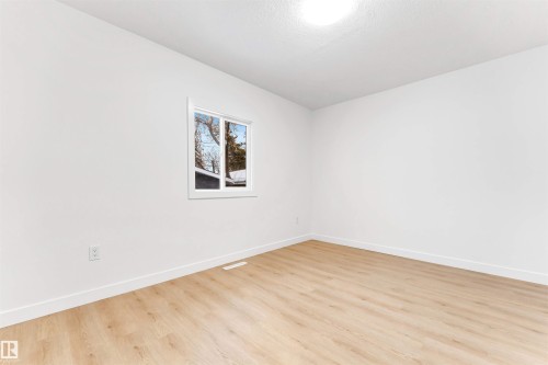 An expansive room featuring light-toned flooring, white walls, and a window providing natural light - 12423 91 Street, Edmonton, AB - Indoor Photo Showing Other Room