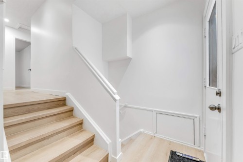 Staircase with light wood treads and white risers, featuring a white railing and light wood flooring - 12423 91 Street, Edmonton, AB - Indoor Photo Showing Other Room