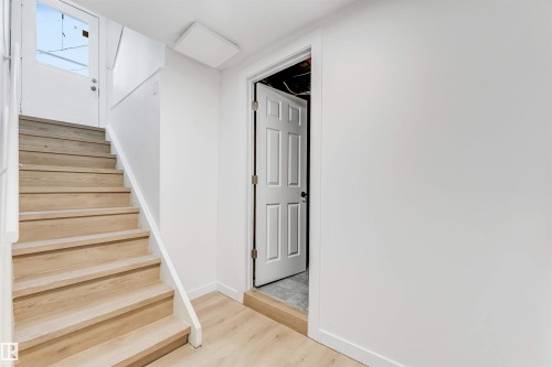 The property features light wood flooring throughout, including a staircase with a white railing - 12423 91 Street, Edmonton, AB - Indoor Photo Showing Other Room