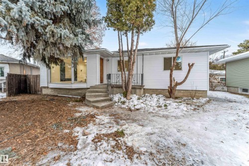 The property features a white exterior, a prominent bay window, and a concrete staircase leading to the entrance - 12423 91 Street, Edmonton, AB - Outdoor