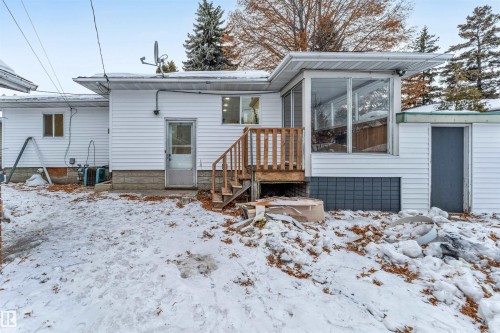 The exterior of the property features white siding, a sunroom with large windows, and a wooden deck with stairs - 12423 91 Street, Edmonton, AB - Outdoor
