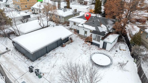 The property features a primary residence with a dark-pitched roof and a separate, detached outbuilding with a flat roof, all situated on a snow-covered lot - 12423 91 Street, Edmonton, AB - Outdoor