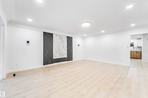 The property features a spacious room with light-toned flooring and white walls, enhanced by recessed lighting and a central ceiling light fixture - 12423 91 Street, Edmonton, AB - Indoor Photo Showing Other Room