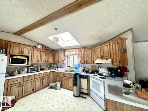 The kitchen features extensive light wood cabinetry, white countertops, a skylight for natural light, and patterned flooring - 50124 Range Road 203, Rural Beaver County, AB - Indoor Photo Showing Kitchen
