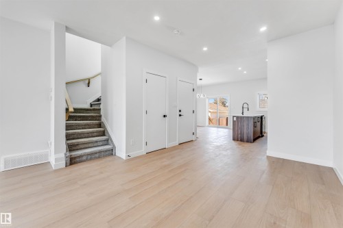 This property features light-toned wood flooring, recessed lighting, and a staircase with carpeted treads and a wooden handrail - 10962 157 Street, Edmonton, AB - Indoor Photo Showing Other Room