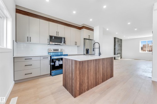 The kitchen features light-colored cabinetry with dark hardware, a white subway tile backsplash, and stainless steel appliances - 10962 157 Street, Edmonton, AB - Indoor Photo Showing Kitchen With Upgraded Kitchen