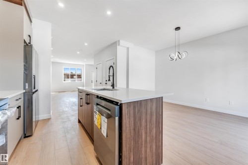 The kitchen features an island with a sink, a built-in dishwasher, and a refrigerator - 10962 157 Street, Edmonton, AB - Indoor Photo Showing Kitchen With Upgraded Kitchen