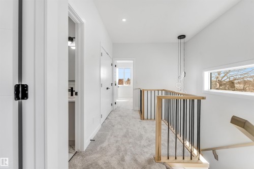 This hallway features light-colored carpeting, white walls, and a modern light fixture - 10962 157 Street, Edmonton, AB - Indoor Photo Showing Other Room