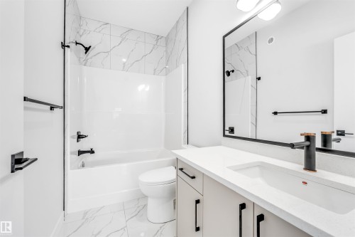 The bathroom features a sleek vanity with a rectangular sink and a modern matte black faucet - 10962 157 Street, Edmonton, AB - Indoor Photo Showing Bathroom