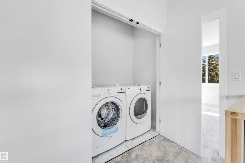 Integrated laundry area with a white front-loading washer and dryer, set on a tiled floor - 10962 157 Street, Edmonton, AB - Indoor Photo Showing Laundry Room
