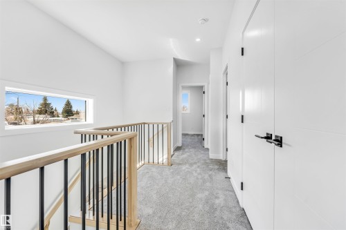The property features a bright hallway with light grey carpeting, white walls, and a horizontal window - 10962 157 Street, Edmonton, AB - Indoor Photo Showing Other Room