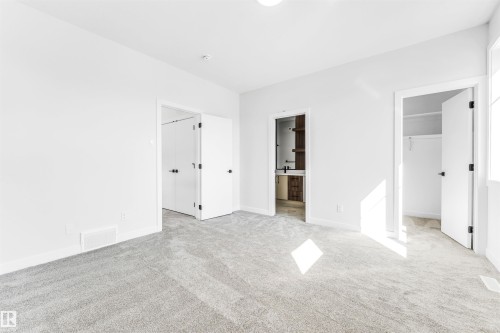 The property features light gray carpet flooring and white walls, creating a bright and airy atmosphere - 10962 157 Street, Edmonton, AB - Indoor Photo Showing Other Room