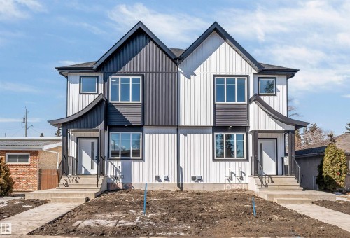 The property features a modern exterior with a white and dark gray facade, large windows, and a covered front entry with railings - 10962 157 Street, Edmonton, AB - Outdoor