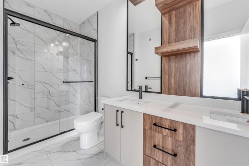 Bathroom featuring a spacious shower with glass enclosure and black trim, a toilet, and a vanity with a white countertop and wood-paneled accents - 10962 157 Street, Edmonton, AB - Indoor Photo Showing Bathroom
