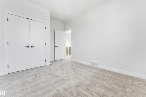 This bright room features light grey carpeting, white walls, and white doors with black hardware - 10962 157 Street, Edmonton, AB - Indoor Photo Showing Other Room