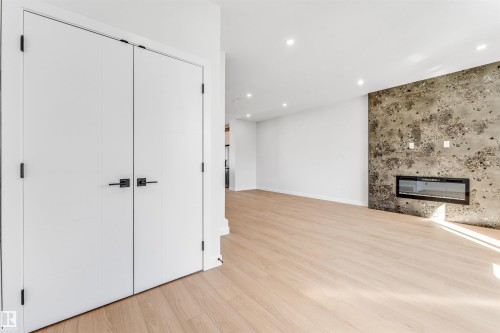 This living space features light wood flooring and recessed lighting - 10962 157 Street, Edmonton, AB - Indoor With Fireplace