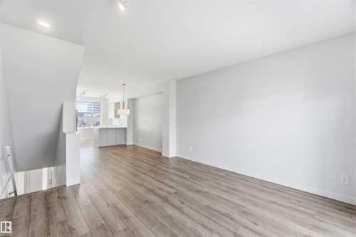 The property features light wood flooring throughout the main living area, with white walls and recessed lighting - 49 100 Jensen Lakes Boulevard, St. Albert, AB - Indoor Photo Showing Other Room