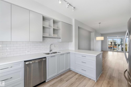The kitchen features light-toned cabinetry, a white subway tile backsplash, and stainless steel appliances including a dishwasher - 49 100 Jensen Lakes Boulevard, St. Albert, AB - Indoor Photo Showing Kitchen With Double Sink With Upgraded Kitchen