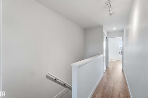 The interior features light wood flooring, white walls, and a white handrail - 49 100 Jensen Lakes Boulevard, St. Albert, AB - Indoor Photo Showing Other Room