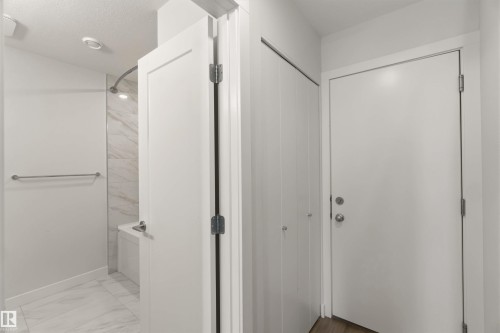 Well-lit bathroom featuring white tiled flooring and a shower with marble-look wall tiles - 49 100 Jensen Lakes Boulevard, St. Albert, AB - Indoor