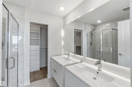 Bathroom featuring dual vanities, a spacious walk-in shower with glass enclosure, and an organized closet with shelving and hanging space - 49 100 Jensen Lakes Boulevard, St. Albert, AB - Indoor Photo Showing Bathroom