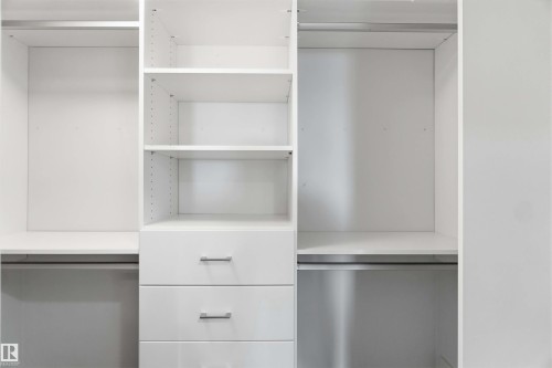 The property features a spacious closet with built-in shelving, hanging rods, and drawers with metal pull handles - 49 100 Jensen Lakes Boulevard, St. Albert, AB - Indoor With Storage