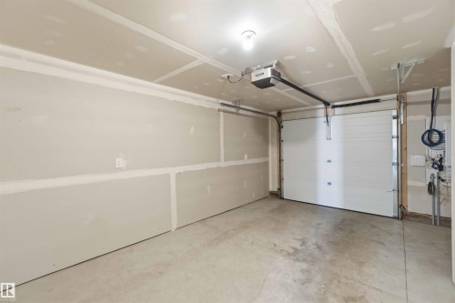 The property features a garage with a concrete floor, an overhead garage door, and an automatic garage door opener - 49 100 Jensen Lakes Boulevard, St. Albert, AB - Indoor Photo Showing Garage