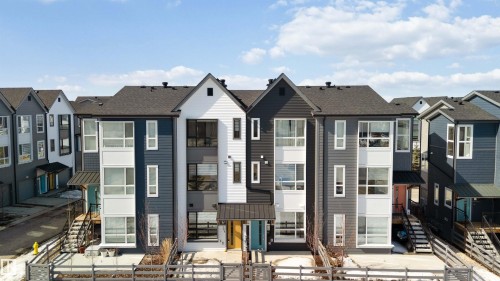 The property features modern townhomes with contrasting dark and light siding, prominent gables, and large windows - 49 100 Jensen Lakes Boulevard, St. Albert, AB - Outdoor With Facade