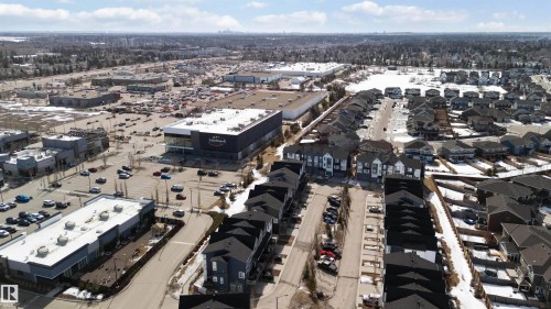 Aerial view showcasing the residential area with detached and attached properties, alongside commercial buildings and associated parking areas - 49 100 Jensen Lakes Boulevard, St. Albert, AB - Outdoor With View
