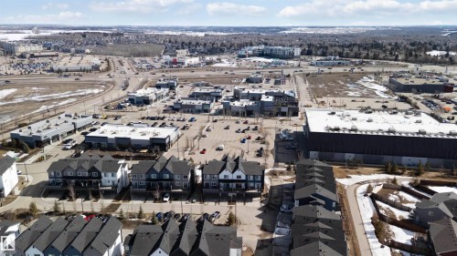 Aerial view showcasing properties with dark-toned roofs, situated near a commercial area with multiple retail buildings and parking lots - 49 100 Jensen Lakes Boulevard, St. Albert, AB - Outdoor With View