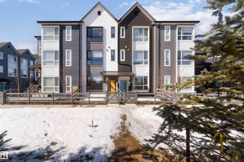 The property features a contemporary exterior with varying shades of gray and white siding, distinct peaked gables, and prominent windows across multiple levels - 49 100 Jensen Lakes Boulevard, St. Albert, AB - Outdoor With Facade