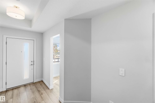 The property features a bright entryway with light-colored flooring, a modern white door with a vertical glass insert, and a ceiling-mounted light fixture - 49 100 Jensen Lakes Boulevard, St. Albert, AB - Indoor Photo Showing Other Room