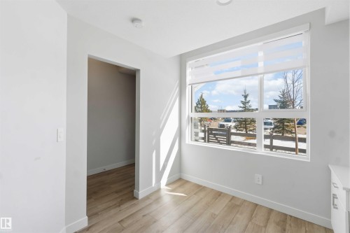 This room features light wood-look flooring and a large window with white blinds, providing natural light - 49 100 Jensen Lakes Boulevard, St. Albert, AB - Indoor Photo Showing Other Room