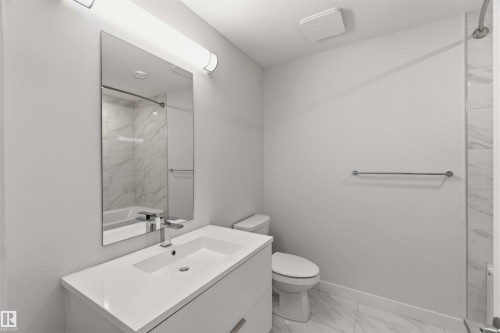 The bathroom features a modern vanity with a white countertop and an integrated sink, a toilet, and a bathtub with a tiled shower surround - 49 100 Jensen Lakes Boulevard, St. Albert, AB - Indoor Photo Showing Bathroom