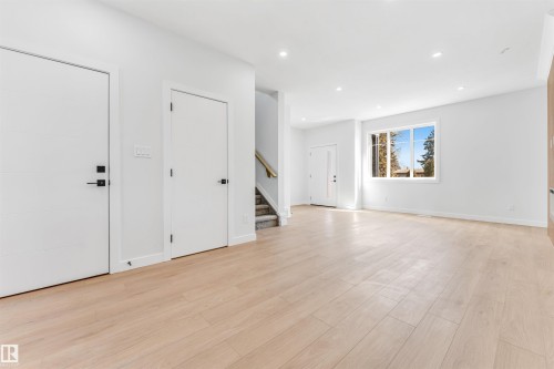 This open concept living area features light-toned flooring, recessed lighting, and a large window providing natural light - 10964 157 Street, Edmonton, AB - Indoor Photo Showing Other Room