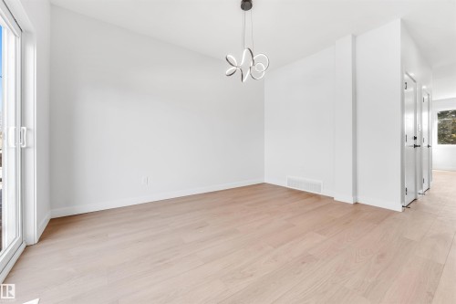 An interior room featuring light wood flooring, white walls, and a modern ceiling light fixture - 10964 157 Street, Edmonton, AB - Indoor Photo Showing Other Room