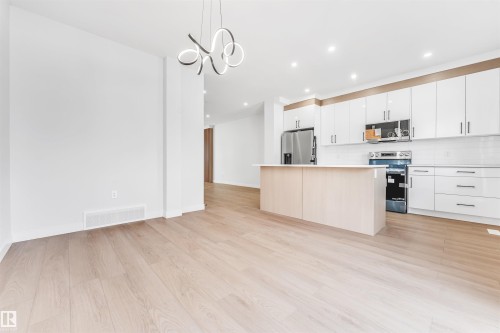 The property features an open-concept living space with light wood flooring, white walls, and a contemporary light fixture - 10964 157 Street, Edmonton, AB - Indoor Photo Showing Kitchen