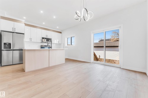 The property features an open kitchen with white cabinetry, stainless steel appliances, and a central island - 10964 157 Street, Edmonton, AB - Indoor Photo Showing Kitchen