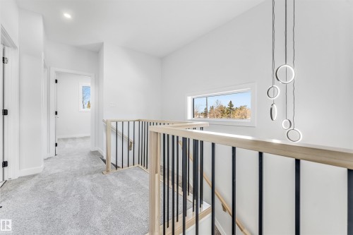 The property features a bright hallway with light grey carpet, white walls, and a modern light fixture - 10964 157 Street, Edmonton, AB - Indoor Photo Showing Other Room