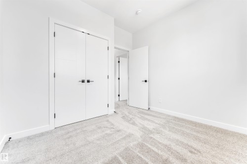 This room features light-colored walls, light-colored carpet, and white doors with dark hardware - 10964 157 Street, Edmonton, AB - Indoor Photo Showing Other Room