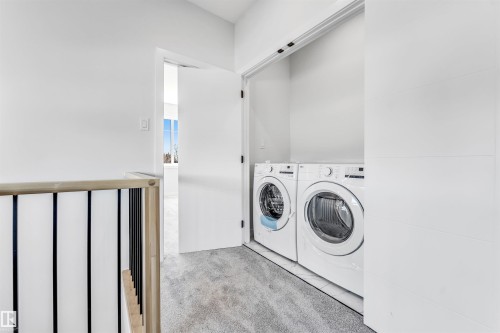 This property features a dedicated laundry area with a washer and dryer, set on a grey carpeted floor - 10964 157 Street, Edmonton, AB - Indoor Photo Showing Laundry Room