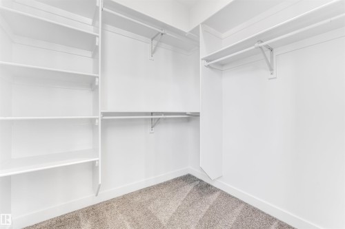 Spacious walk-in closet featuring white built-in shelving, hanging rods, and plush carpet flooring - 10964 157 Street, Edmonton, AB - Indoor With Storage